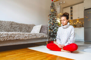 Holiday stress relief tips used by a woman meditating on her living room floor
