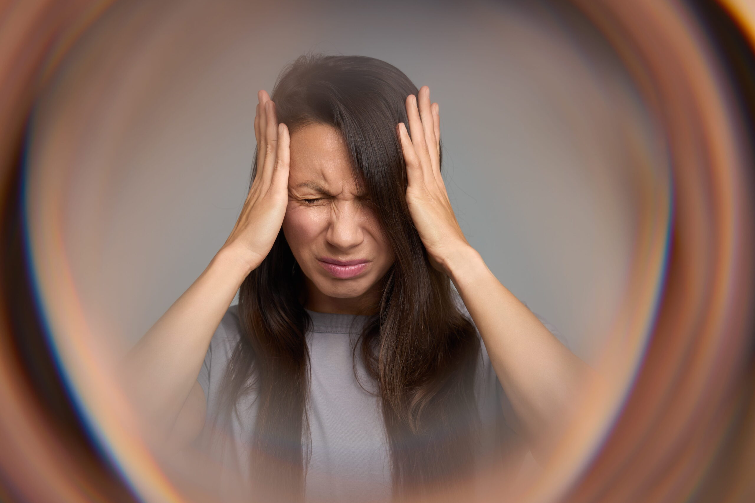 Woman holding her head in distress, illustrating the sensory overwhelm and emotional exhaustion associated with autistic burnout symptoms