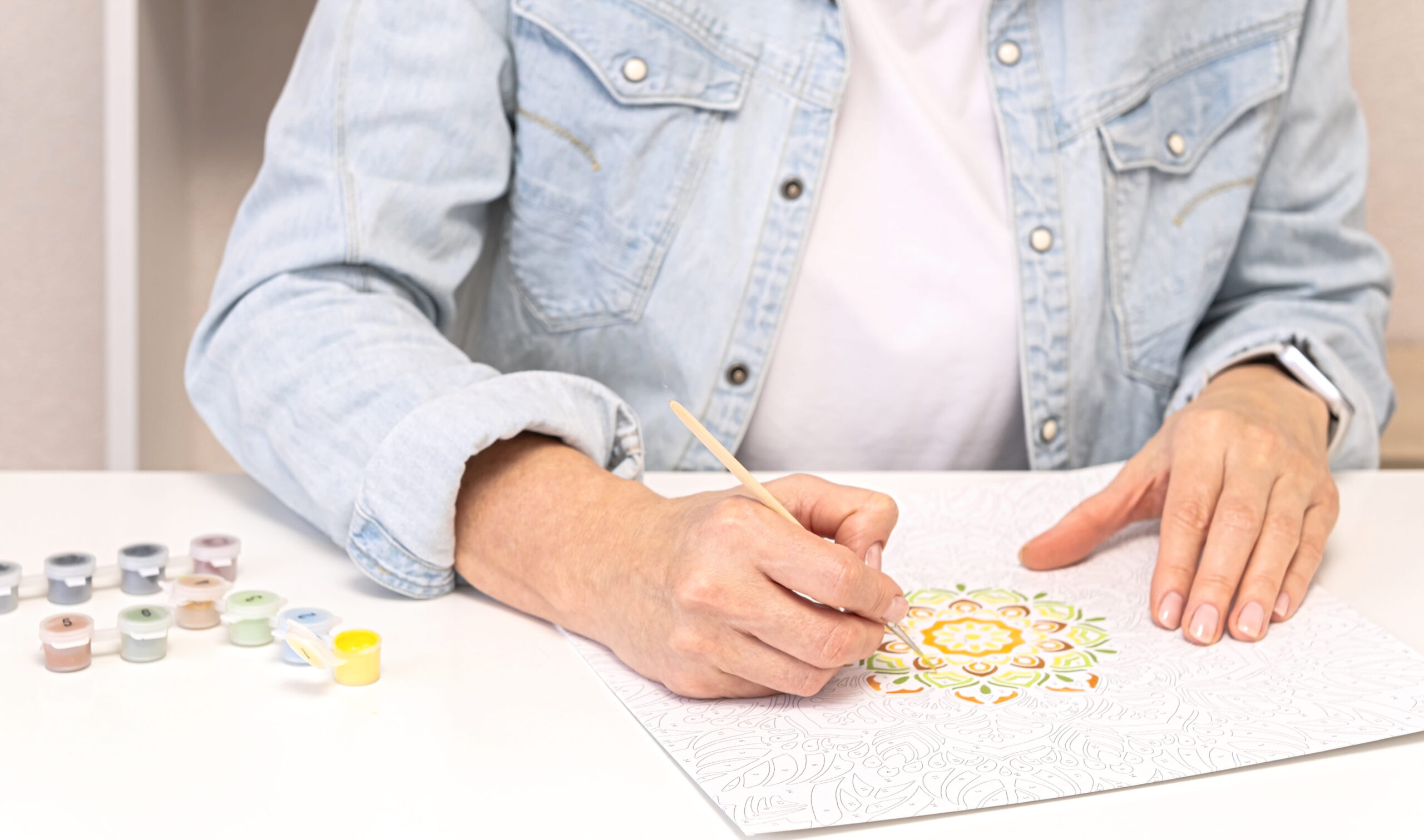 A person painting a mandala using a paint-by-numbers kit, showcasing the benefits of art therapy for relaxation and emotional expression.