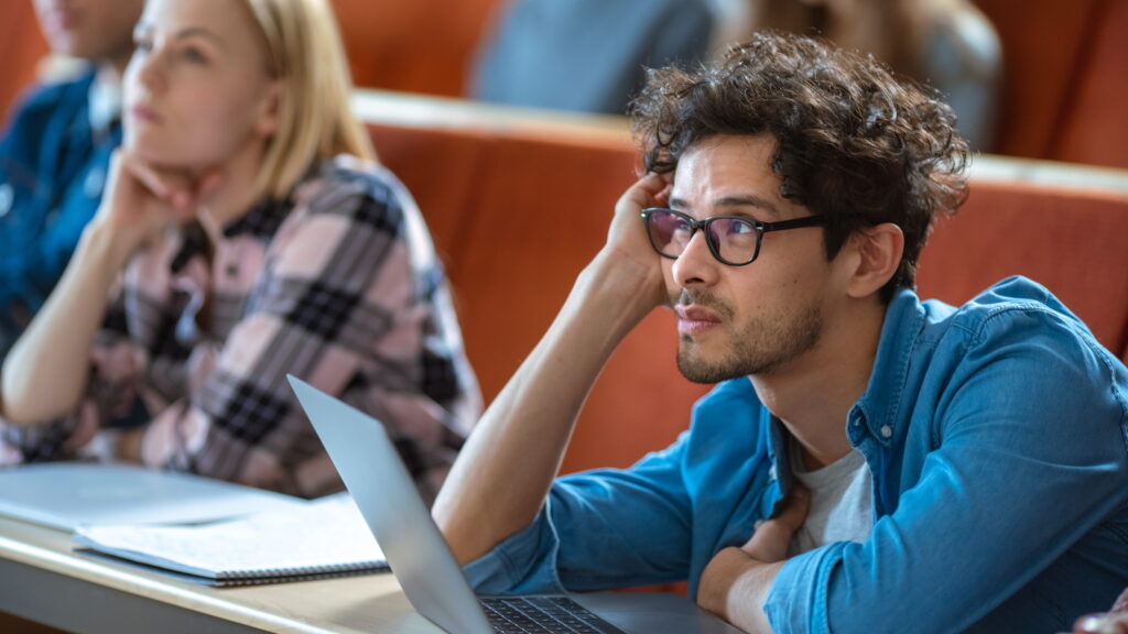 Young adult with ADHD using a laptop in a classroom setting.