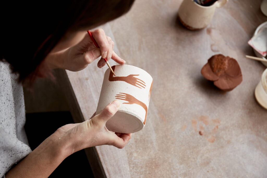 Person painting pottery as part of a creative art therapy activity for anxiety.